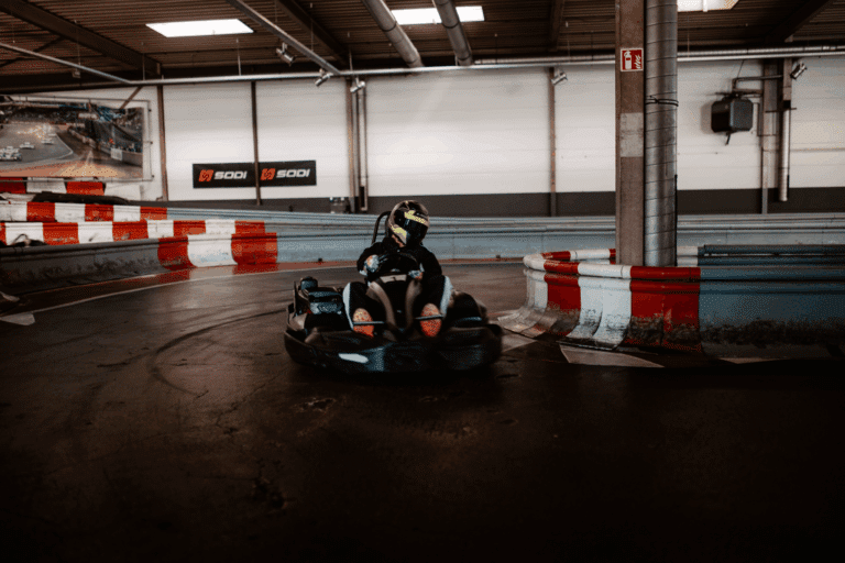 Ein einzelnes Kart in dunklem Overall fährt in einer Kurve beim Kartcenter Cologne, Kartfahren Köln.