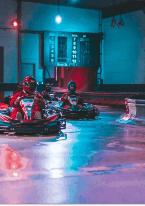 Mehrere Karts mit Abstand fahren im Wettkampf in einer Kurve der Strecke im Kartcenter Cologne beim Kartfahren Köln.