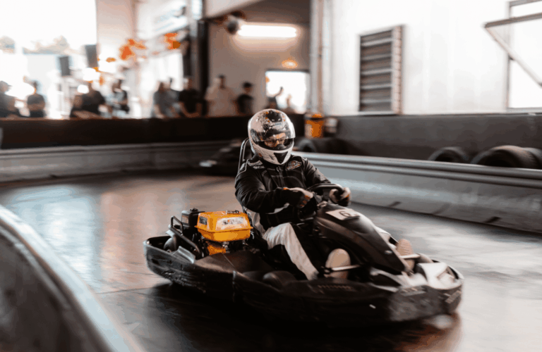 Ein einzelnes Kart in der Kurve beim Wettkampf auf der Rennstrecke im Kartcenter Cologne, Zuschauer beobachten das Kartfahren Köln.
